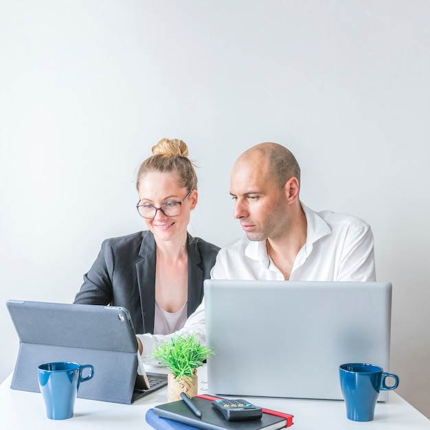 Empresarios masculinos y femeninos que usan la computadora portátil en el lugar de trabajo