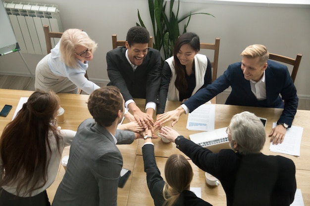 Los empresarios multirraciales juntan las manos en la reunión del equipo del grupo