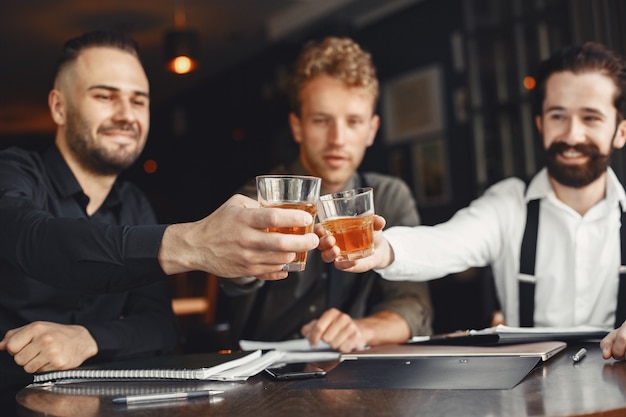 Empresarios en negociaciones. Hombres con alcohol sentados a la mesa. Los amigos están hablando.