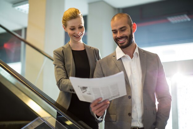 Empresarios de pie en escaleras mecánicas con equipaje