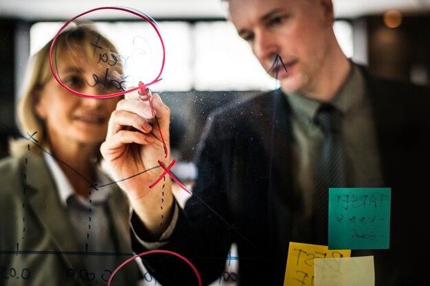 Empresarios planeando en una pared de vidrio