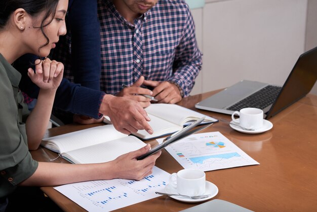 Empresarios recortados discutiendo gráficos y diagramas en la oficina