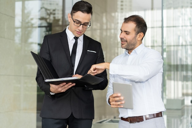 Empresarios sonrientes discutiendo documento comercial en la carpeta