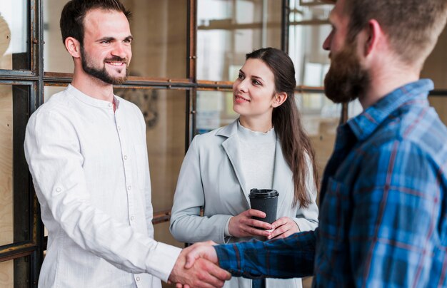 Empresarios sonrientes que sacuden la mano en la oficina