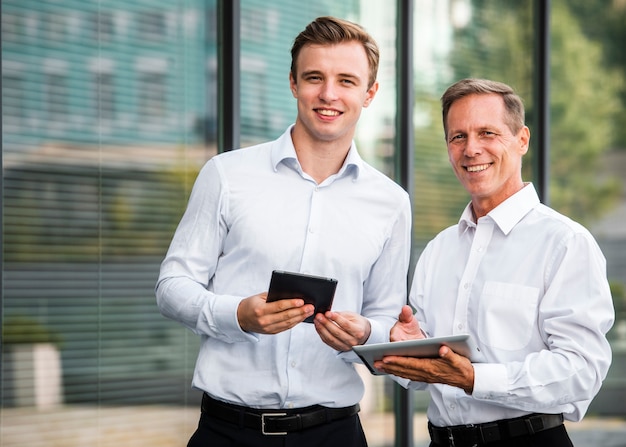 Empresarios con tabletas mirando a cámara