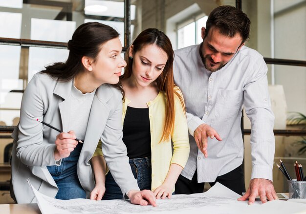 Empresarios trabajando en el plano azul en el lugar de trabajo