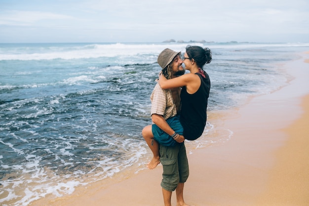 Enamorados divirtiéndose en la orilla del mar