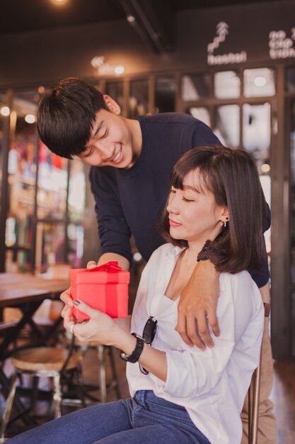 Enamorados sonriendo mientras la chica sujeta un regalo rojo