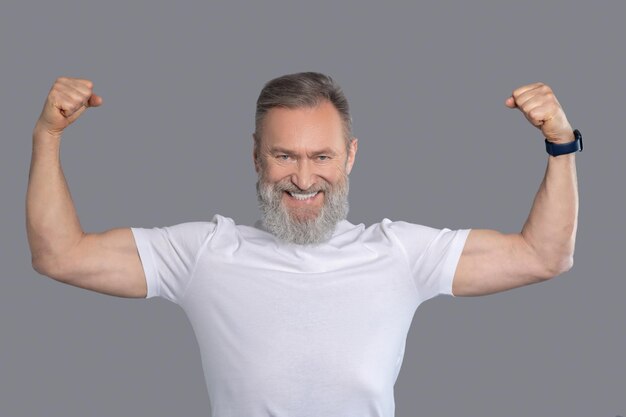 Encajar. Un hombre maduro con una camiseta blanca mostrando sus músculos