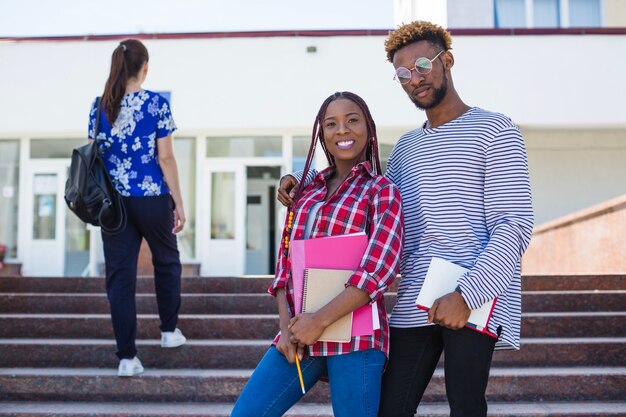 Encantado estudiantes negros posando en las escaleras