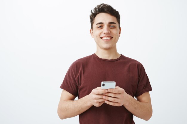 Encantado de tener grandes amigos en línea. Modelo masculino feliz guapo en traje casual con smartphone