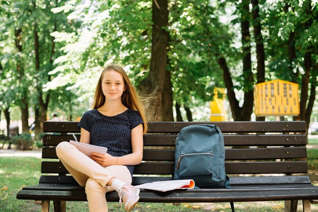 Encantador estudiante con libro en el parque