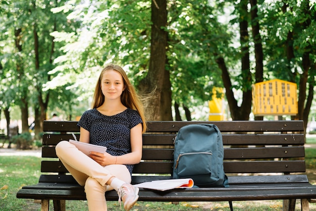 Encantador estudiante con libro en el parque
