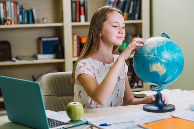 Encantador estudiante trabajando con globo en escritorio