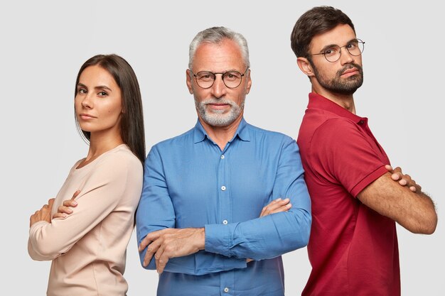 encantador hermano, hermana y su anciano padre posando contra la pared blanca