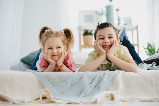 Encantador niño y niña se encuentran en la cama