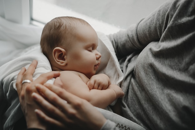 Encantador niño recién nacido duerme en los brazos de la madre