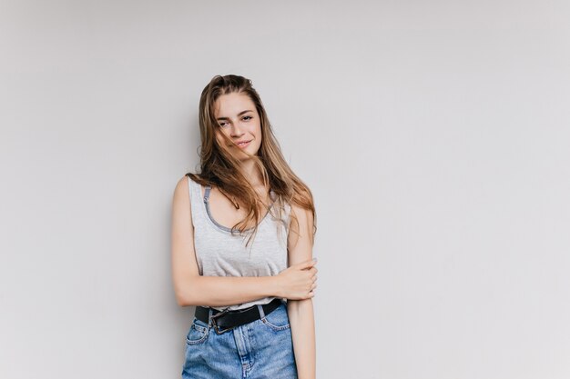 Encantadora chica caucásica en ropa casual posando. Hermosa mujer joven de pelo largo con piel ligeramente bronceada aislada.