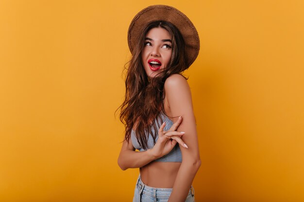 Encantadora chica con piel bronceada mirando hacia arriba con una sonrisa