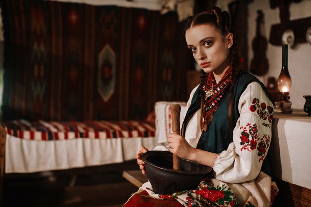 Encantadora chica ucraniana en un vestido tradicional cocinando en la cocina tradicional