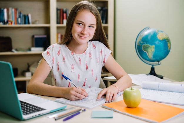 Encantadora colegiala posando en el escritorio