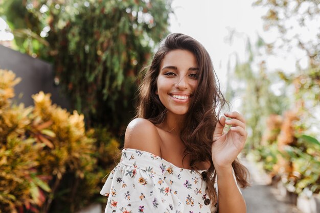 Encantadora dama amable sonrisas en la pared de los árboles