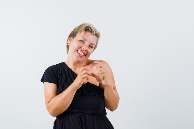 Encantadora dama en blusa negra sosteniendo algo mientras sonríe y parece feliz