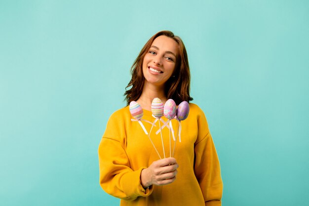 Encantadora dama bonita en ropa brillante posando con huevos de Pascua sobre pared brillante. Preparándose para las vacaciones. Celebración de pascua