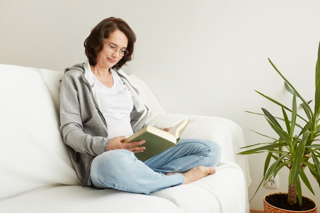 Encantadora dama de mediana edad disfrutando de estar en casa y leer