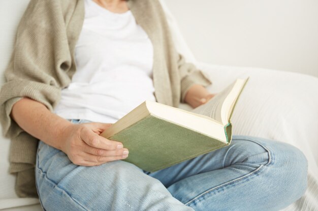 Encantadora dama de mediana edad disfrutando de estar en casa y leer