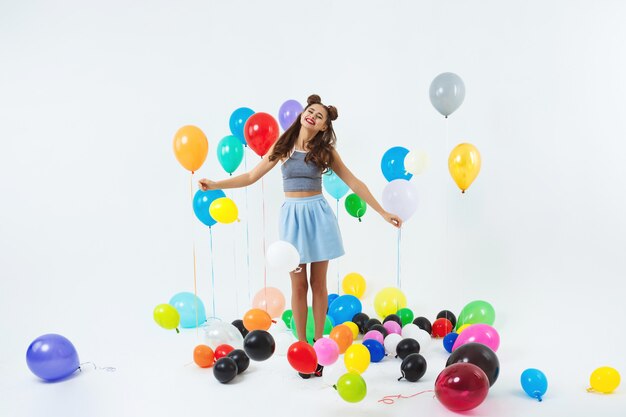 Encantadora dama en ropa de moda se ve feliz sosteniendo un montón de globos