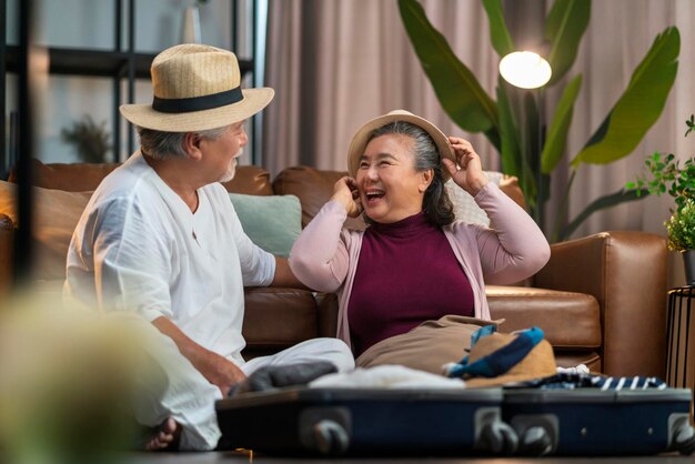 Encantadora felicidad, ancianos, casarse con una pareja de jubilados, preparar la maleta de equipaje después de que el cierre de covid haya terminado para viajar al extranjero de nuevo. Pareja asiática organiza el concepto de viaje de maleta de tela