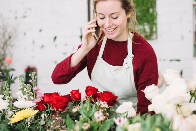 Foto gratuita encantadora floristería hablando por teléfono inteligente