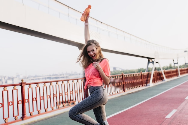 Encantadora ganadora posando después del maratón. retrato al aire libre de una niña encantadora que expresa emociones positivas en el estadio.