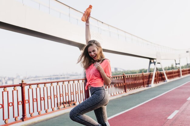 Encantadora ganadora posando después del maratón. Retrato al aire libre de una niña encantadora que expresa emociones positivas en el estadio.