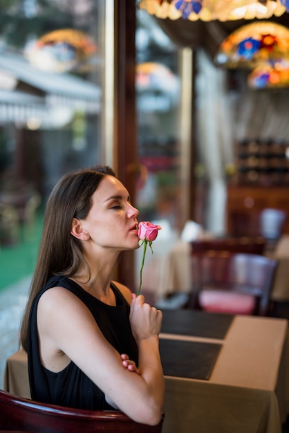 Encantadora joven con flor en la mesa