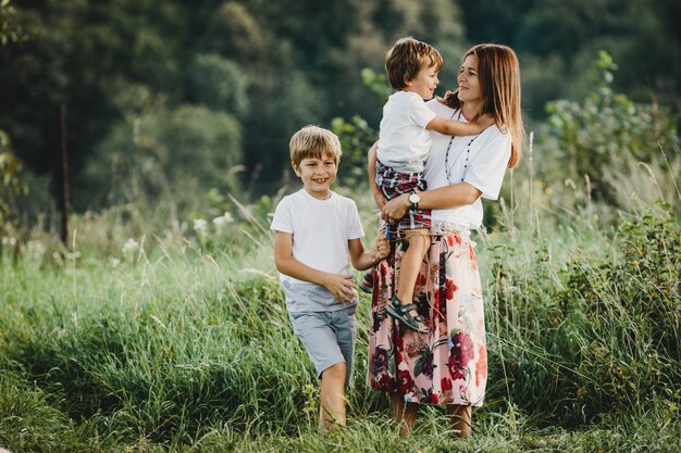 Encantadora joven madre camina con sus pequeños hijos a través