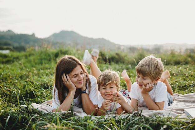 Encantadora joven madre se divierte con sus pequeños hijos mintiendo