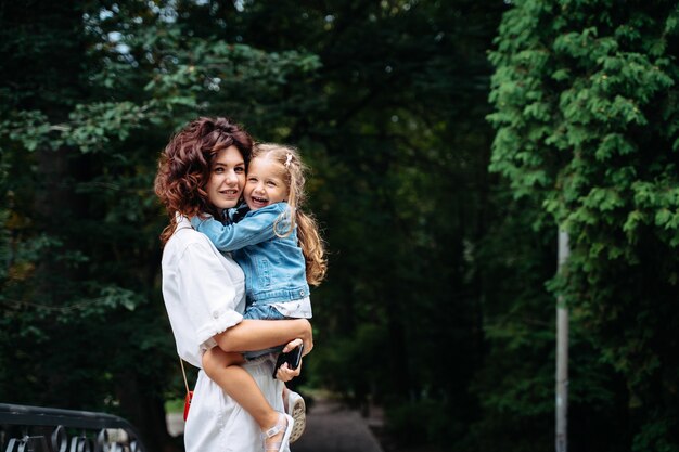 Encantadora joven madre e hija en un día soleado en el parque, familia feliz