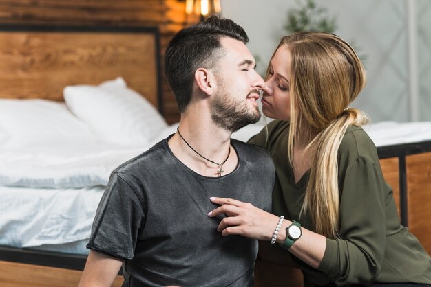 Encantadora joven pareja besándose en el dormitorio