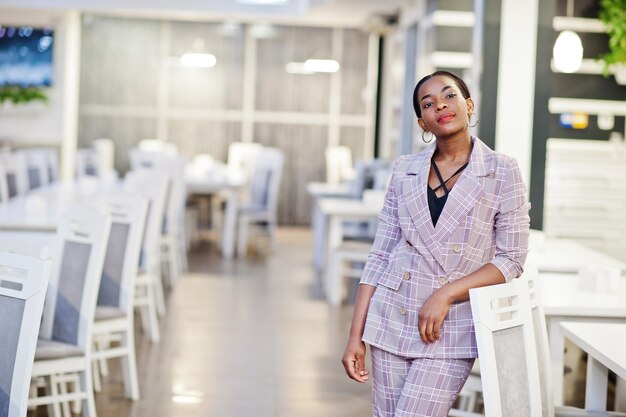 Encantadora mujer afroamericana con chaqueta posando en el restaurante