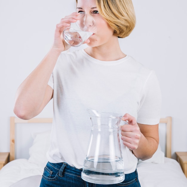 Encantadora mujer agua potable en la cama