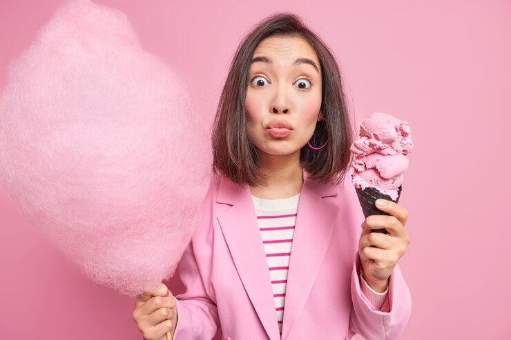 Foto gratuito encantadora mujer asiática sorprendida mira fijamente no se mantiene a dieta o cuenta calorías sostiene hilo de caramelo y helado de cono grande en gofre se permite comer un tratamiento azucarado durante el día libre