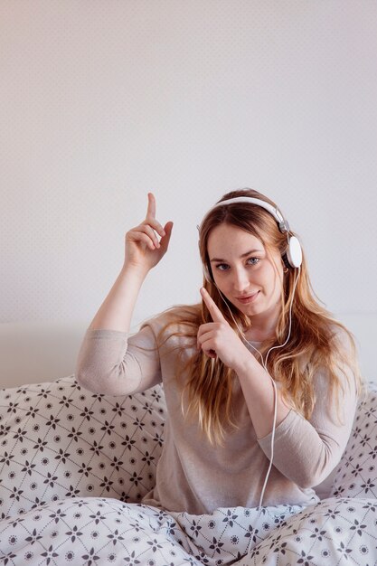 Encantadora mujer en auriculares apuntando hacia arriba