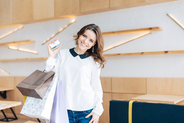 Encantadora mujer con bolsas de papel y tarjeta de crédito