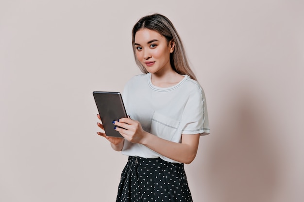 Encantadora mujer en camiseta blanca con tableta de computadora