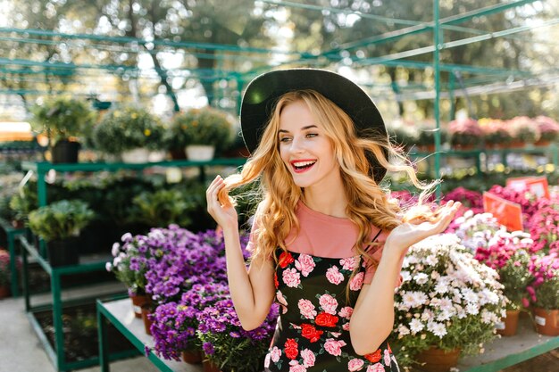 Encantadora mujer europea disfrutando de un buen día. Alegre mujer ciega divirtiéndose en invernadero con flores.