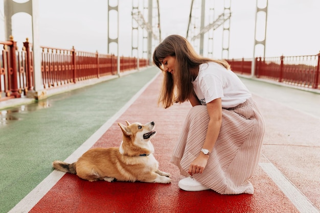 Encantadora mujer con falda rosa y camiseta blanca entrenando con su perro afuera