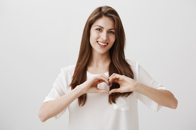 Encantadora mujer feliz sonriente mostrando gesto de corazón