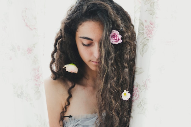 Foto gratuita encantadora mujer con flores cerca de la cortina